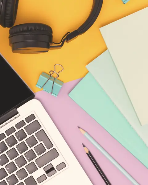 Scrivania colorata con portatile, cuffie e quaderni