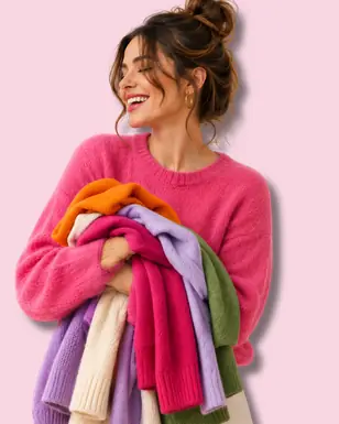 Donna sorridente con in braccio maglioni colorati